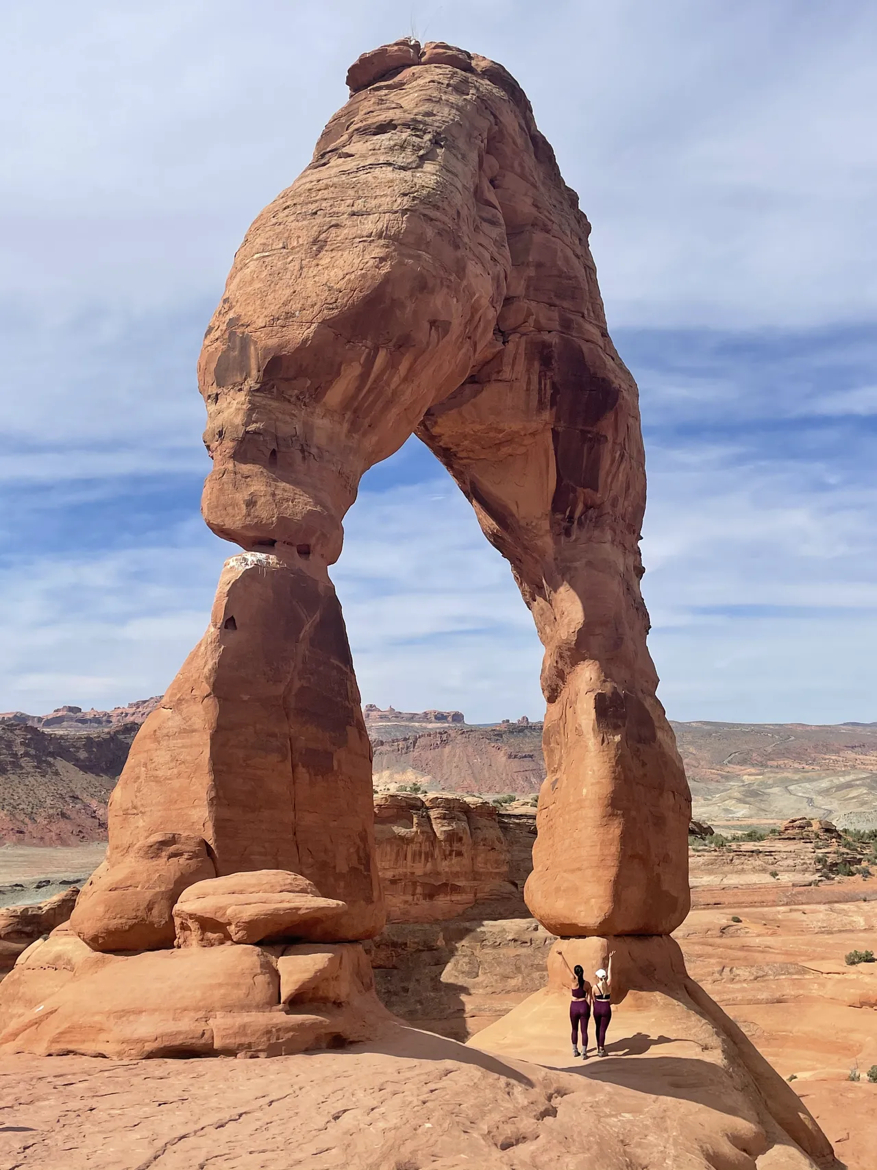 two girls posing in front of delicate arch in moab utah