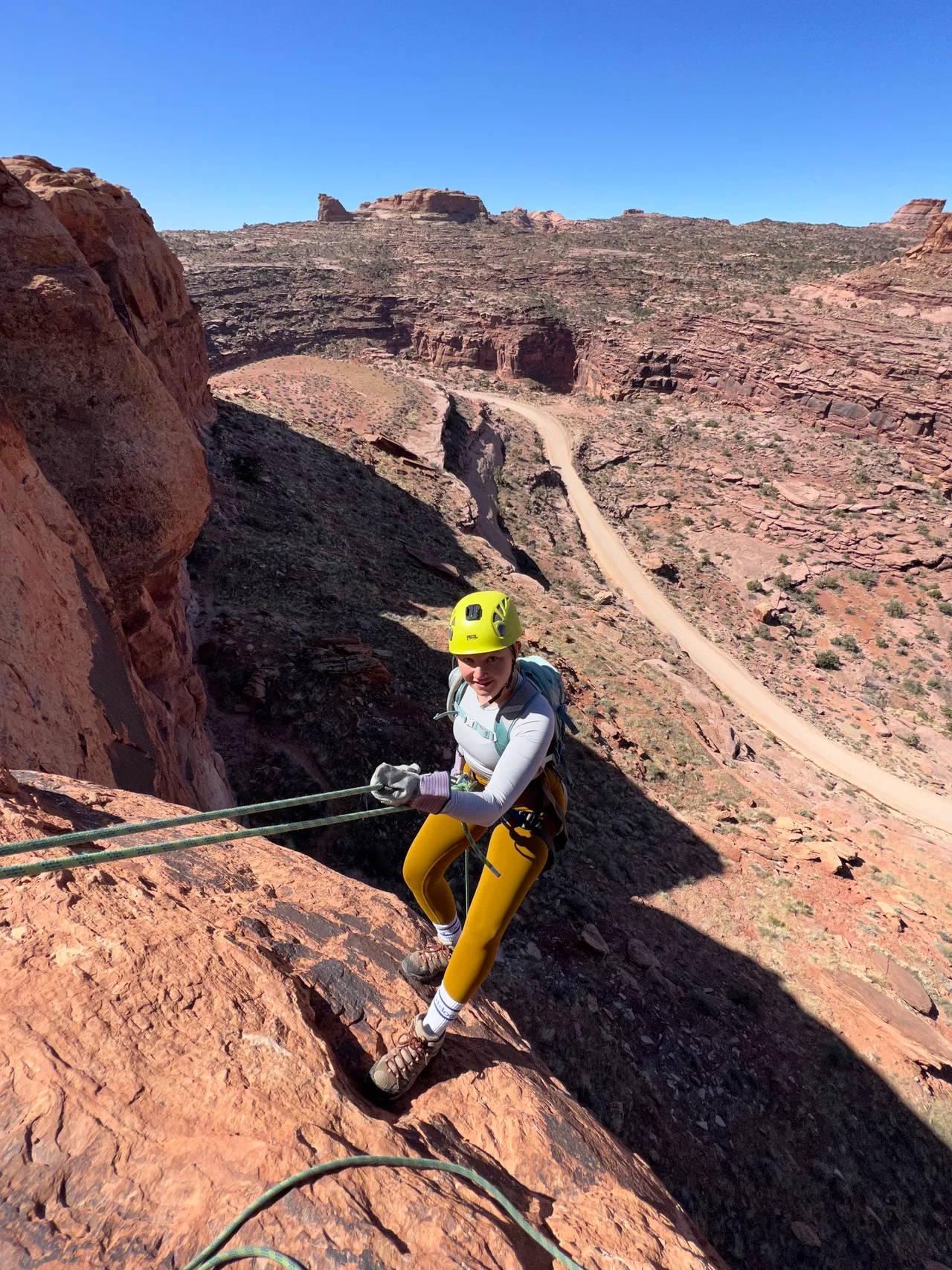 a white girl hanging above a cliffside before she rappels down a cliff in moab utah