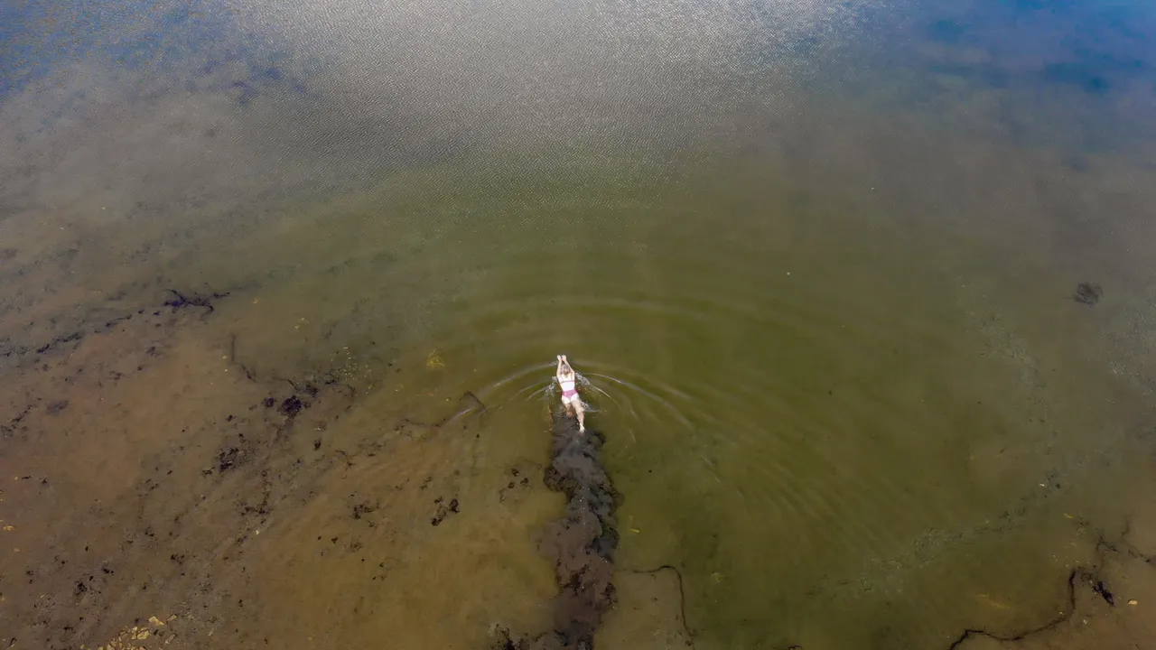 a girl swimming in an alpine lake aerial view