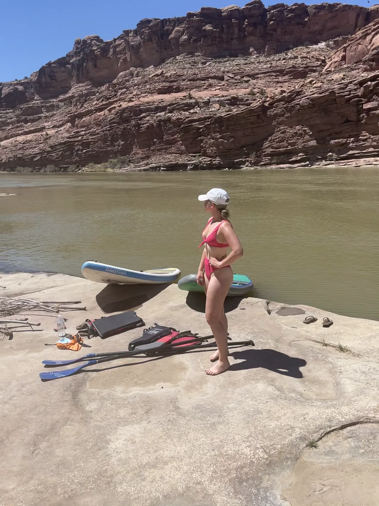 a girl posing in a swimsuit in front of her SUP at the moab utah river