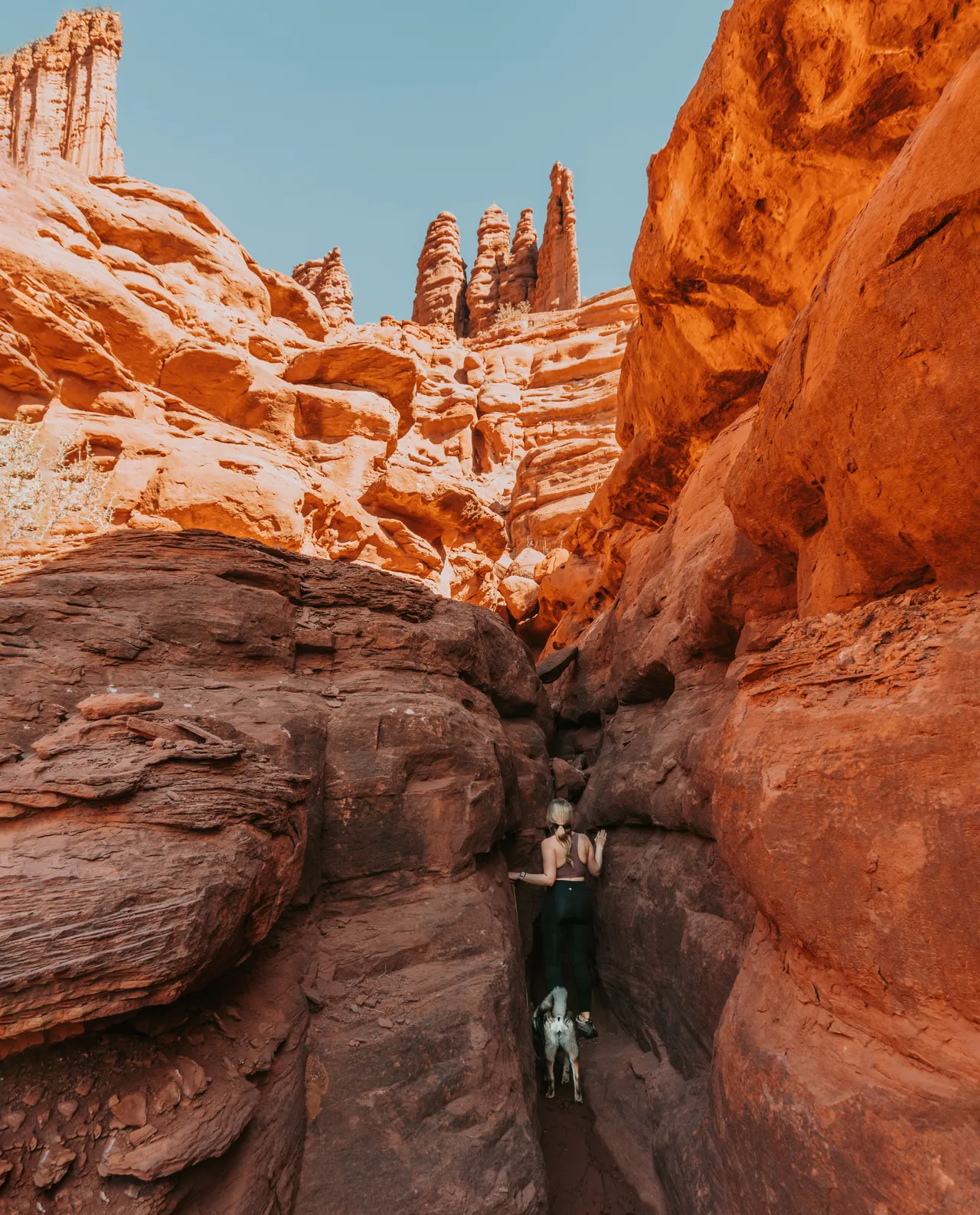 a girl and her dog going through a slot canyon in moab