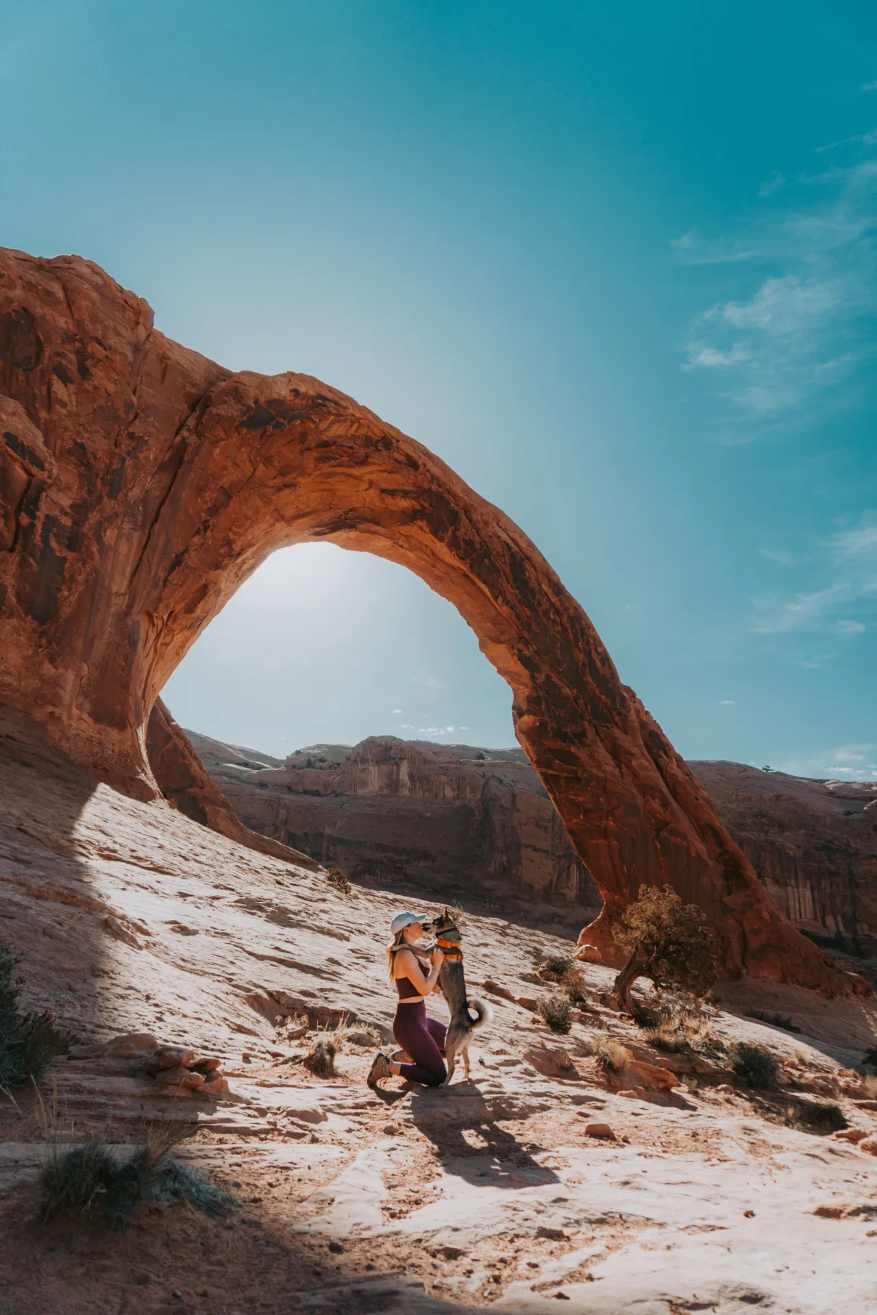 a girl and her dog at corona arch in moab utah