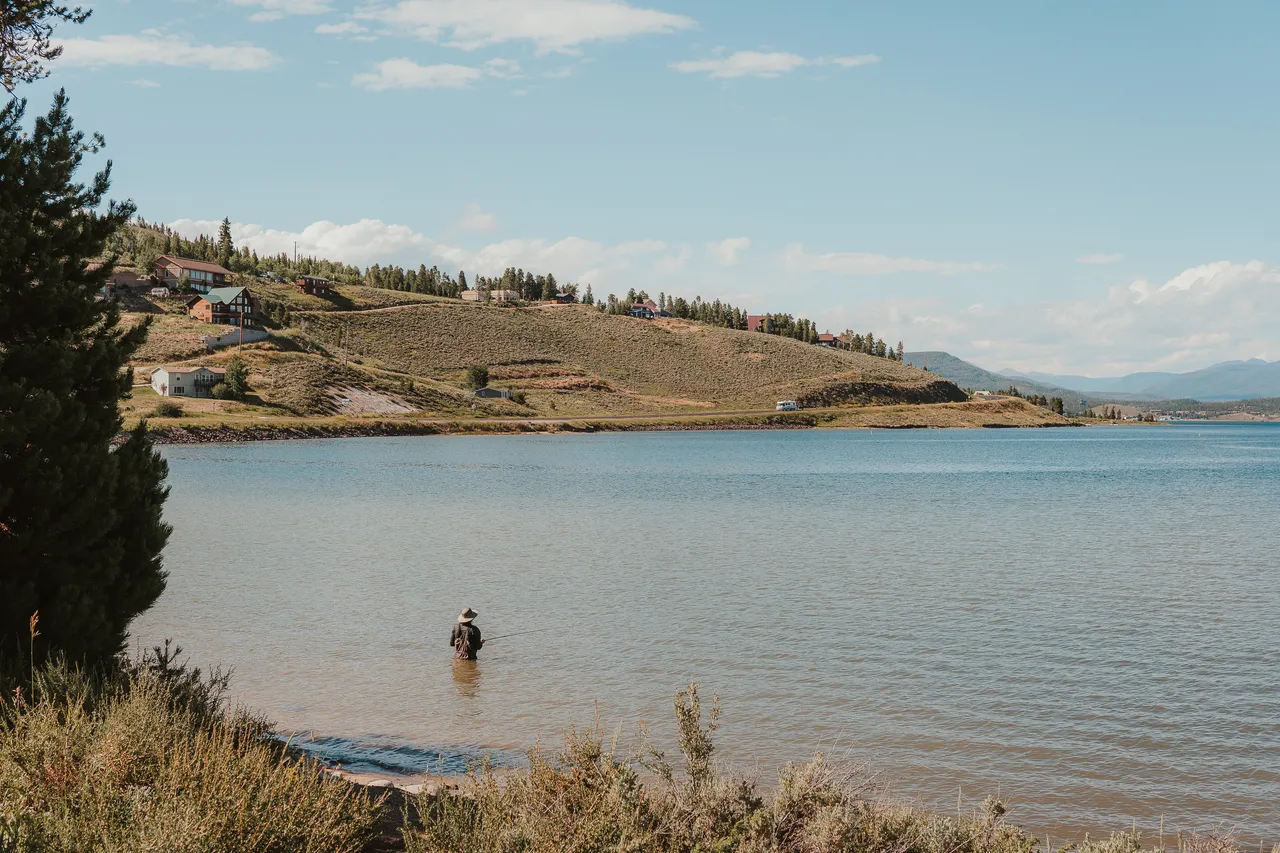 a man fishing in a lake in colorado