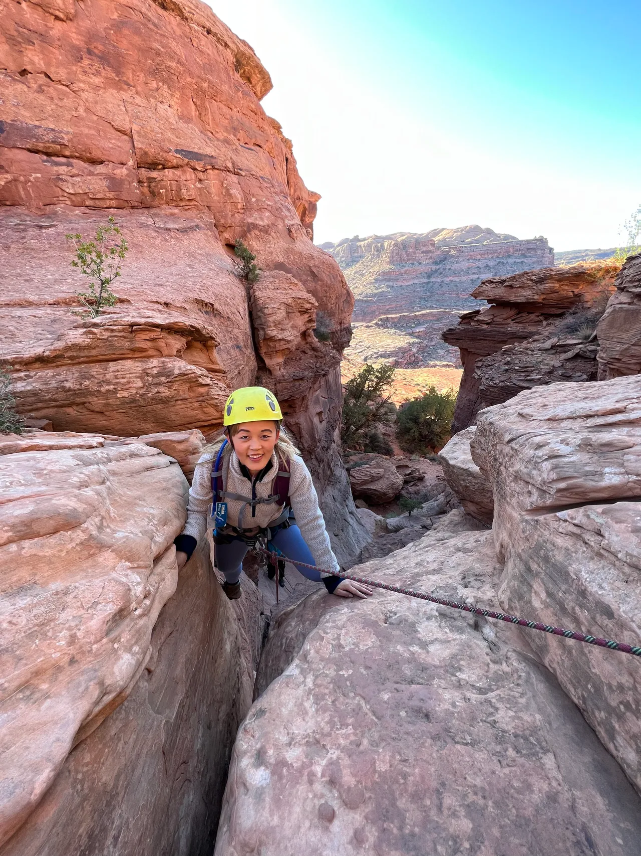 an asian girl above a gap while climbing in moab utah