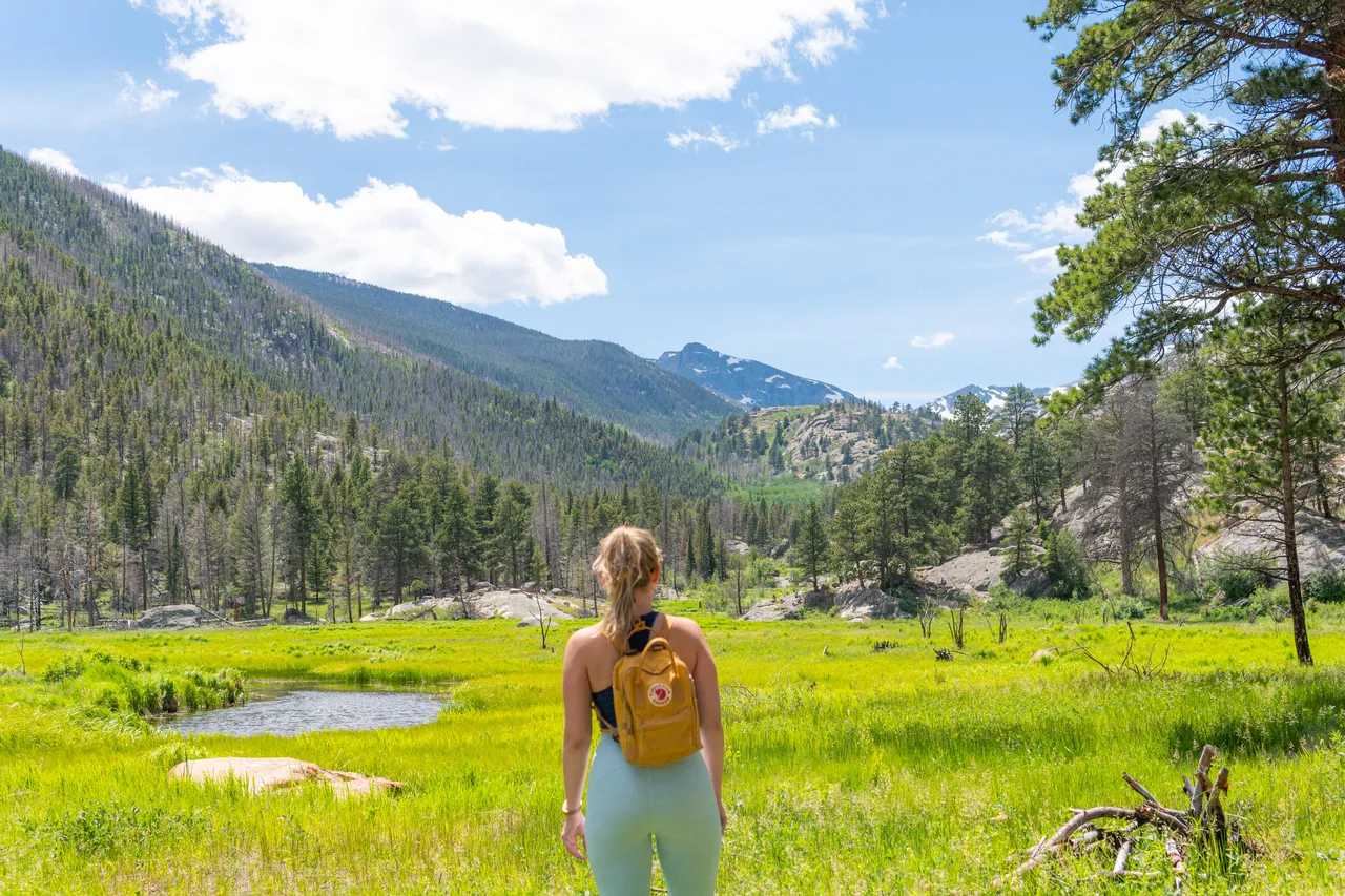 Standing in a green mountain meadow in Rocky Mountain National Park with a Fjallraven backpack, summer 2020