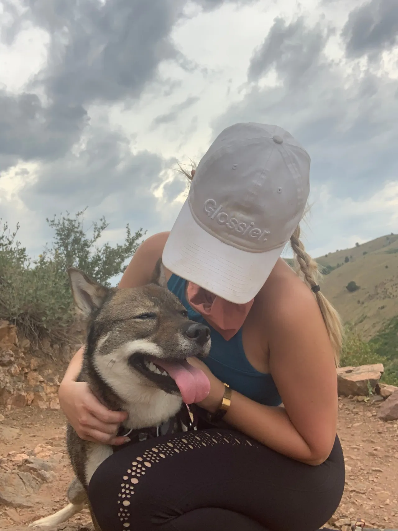 Sora giving kisses on a trail in Colorado, wearing a Glossier hat