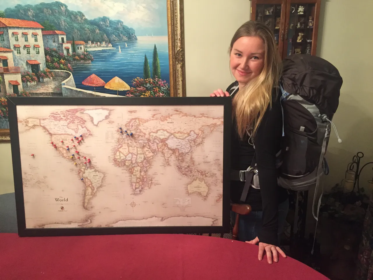 Posing with a world map and my backpack before my first independent international trip