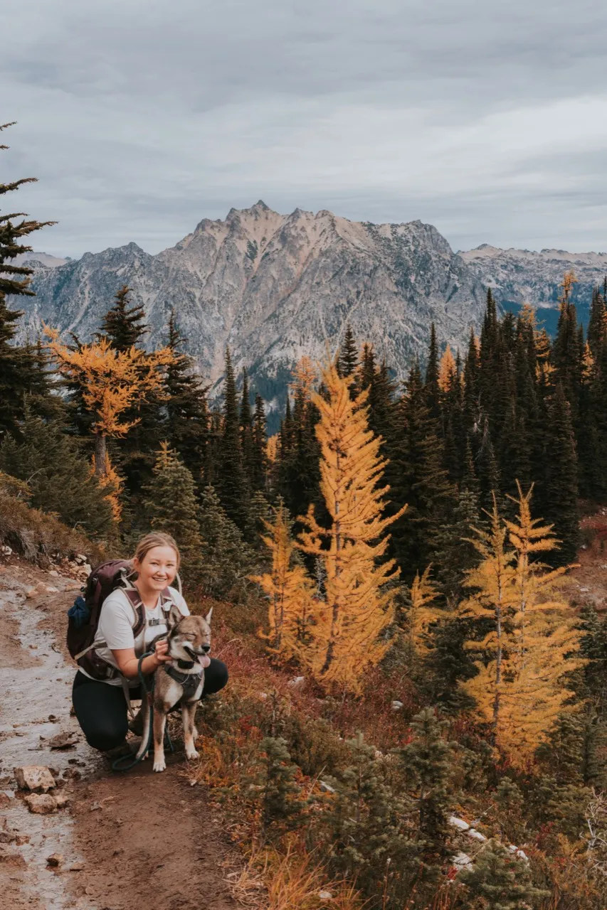 The author and Sora beside golden larches with mountain peaks behind them