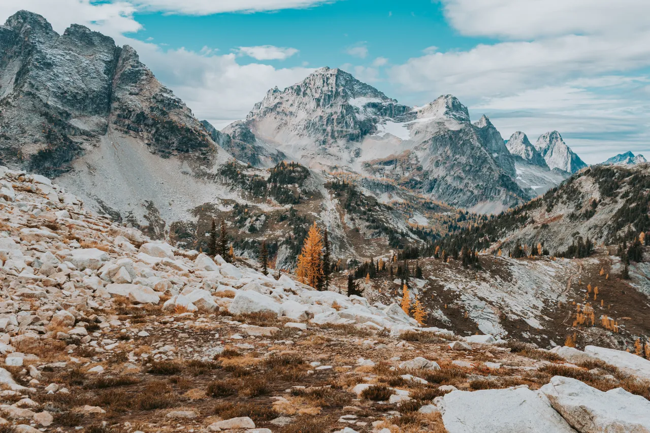 North Cascades peaks above golden larches and a rocky slope at Maple Pass