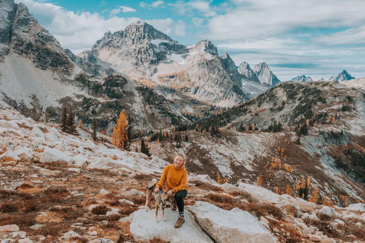 The author and Sora beneath mountain peaks and golden larches on the Maple Pass hike
