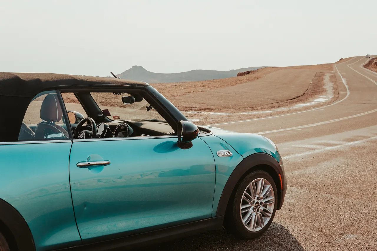 Teal MINI Cooper convertible parked on the winding road near the summit of Pikes Peak, Colorado