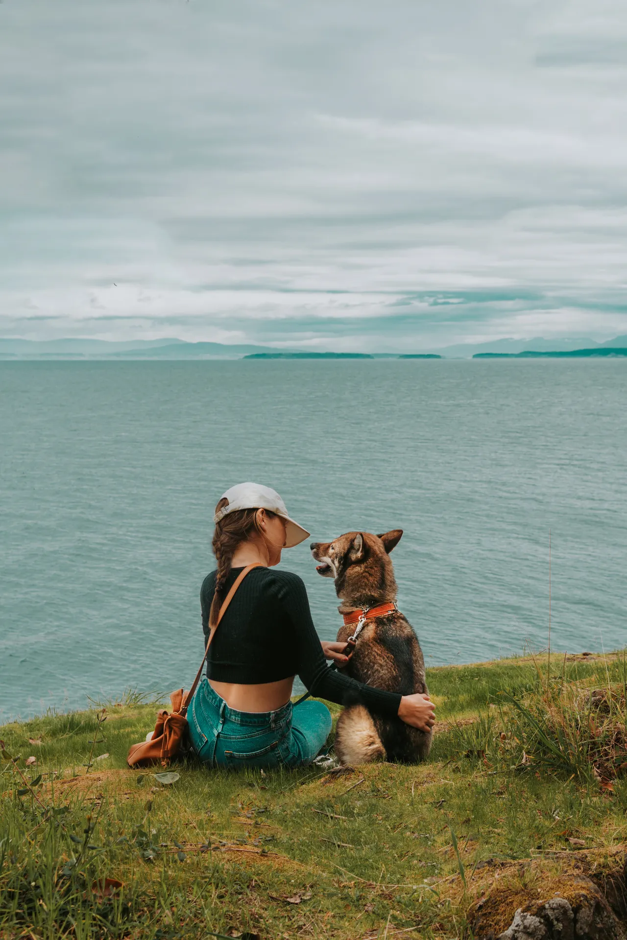 Sitting with Sora on a grassy cliff overlooking the water on a Pacific Northwest island
