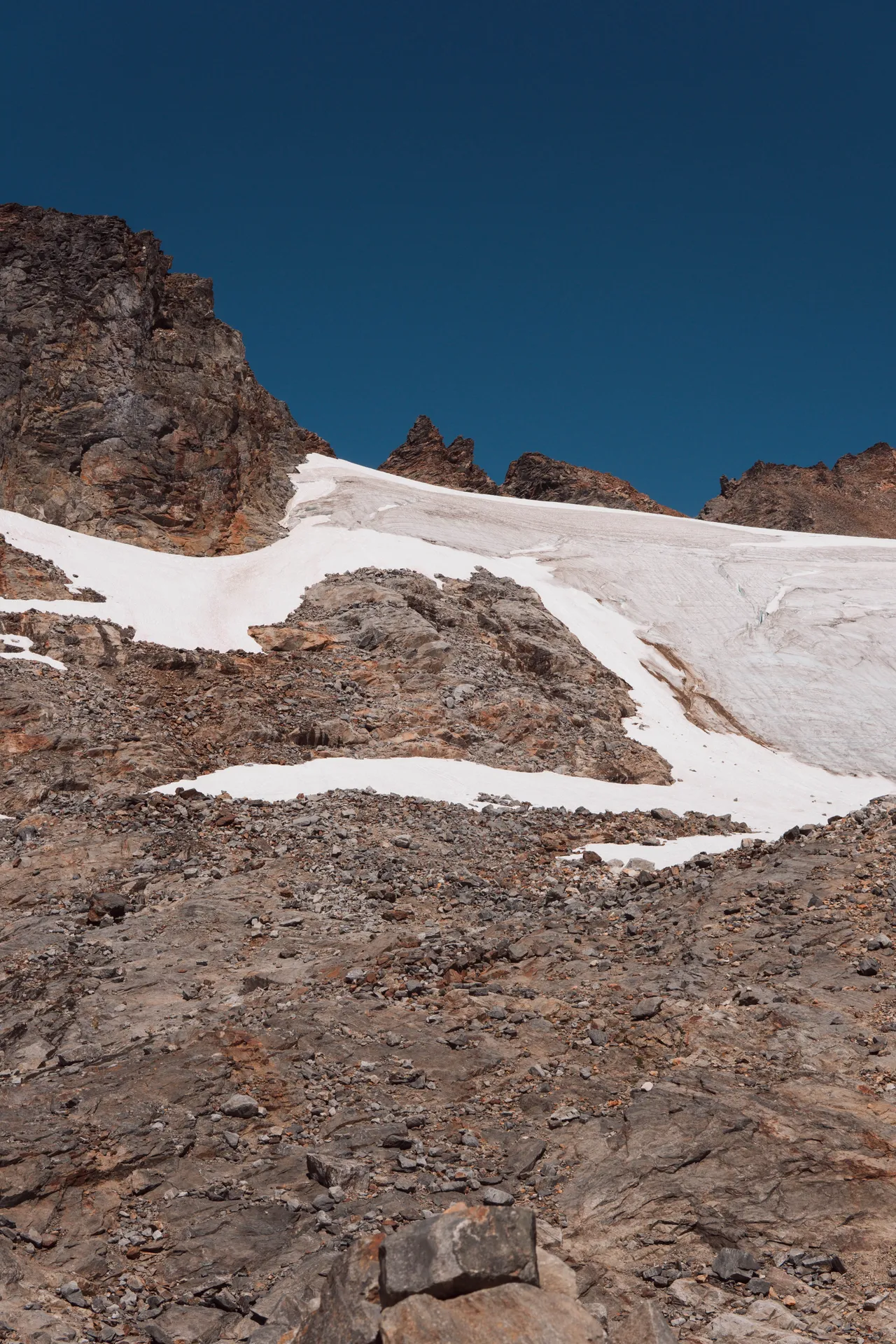 Sahale Glacier up close — snow and ice clinging to dark rocky peaks against deep blue sky
