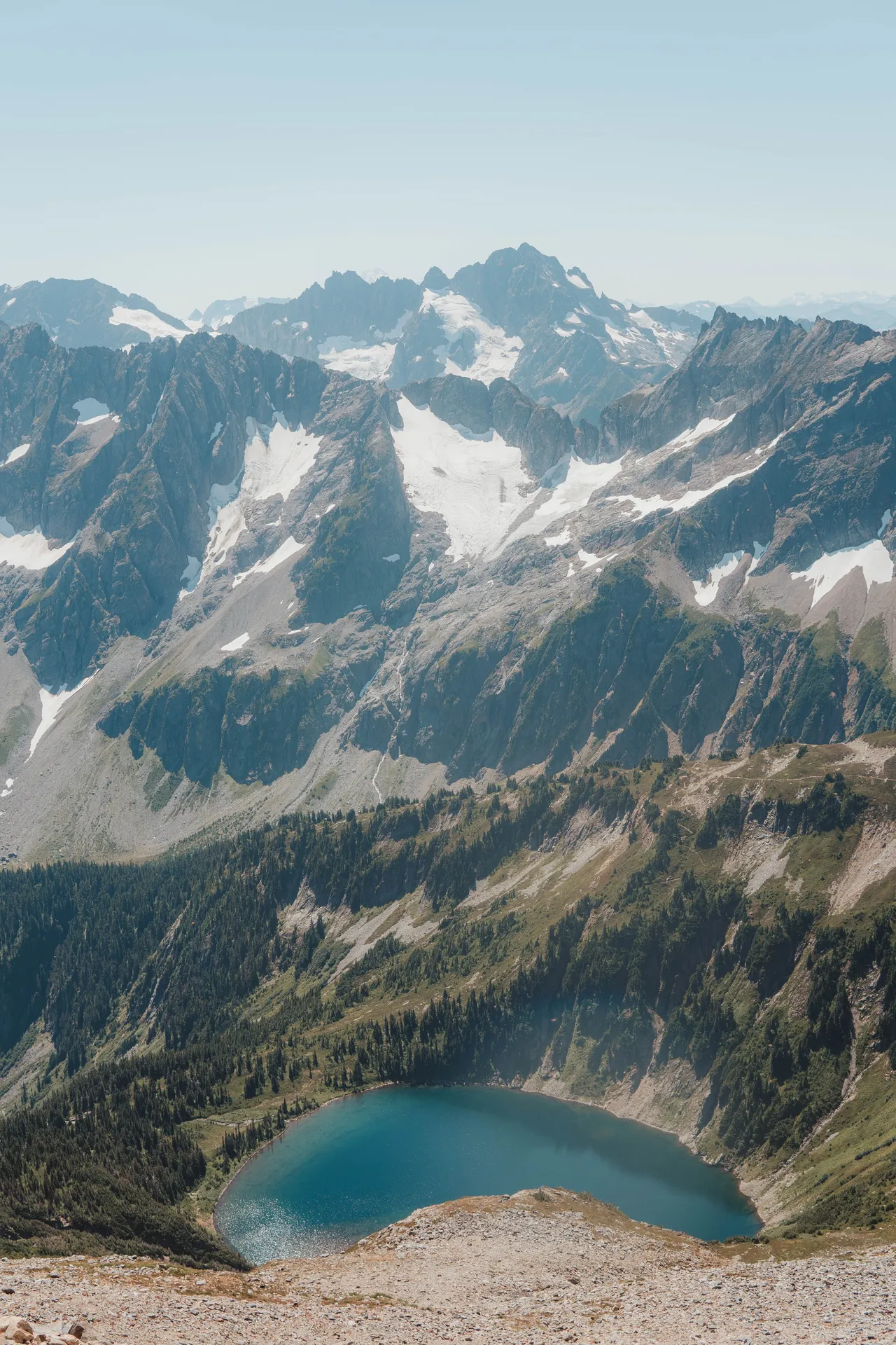 Turquoise alpine lake viewed from high on Sahale Arm with glaciated peaks behind