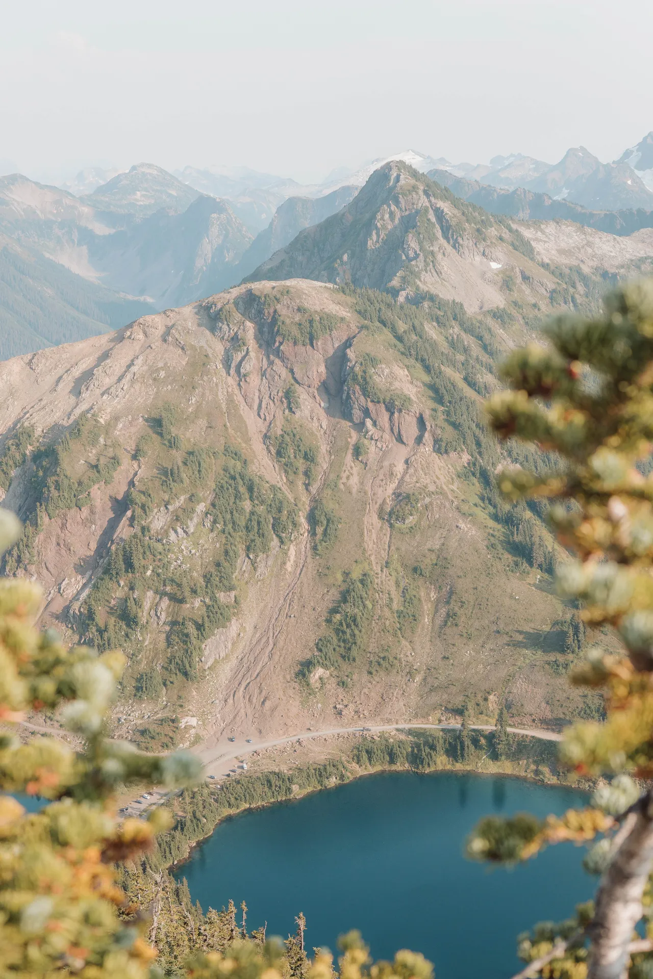 View of an alpine lake and layered mountain peaks framed by trees on the Winchester Mountain hike