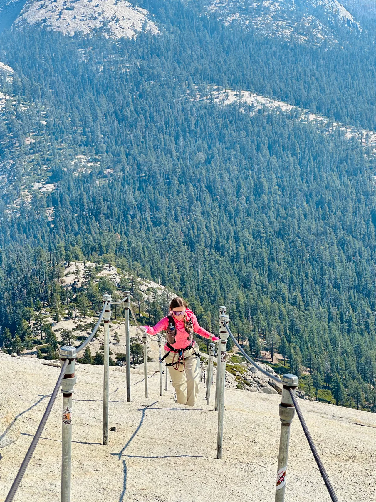 Climbing the Half Dome cables above Yosemite's forested slopes