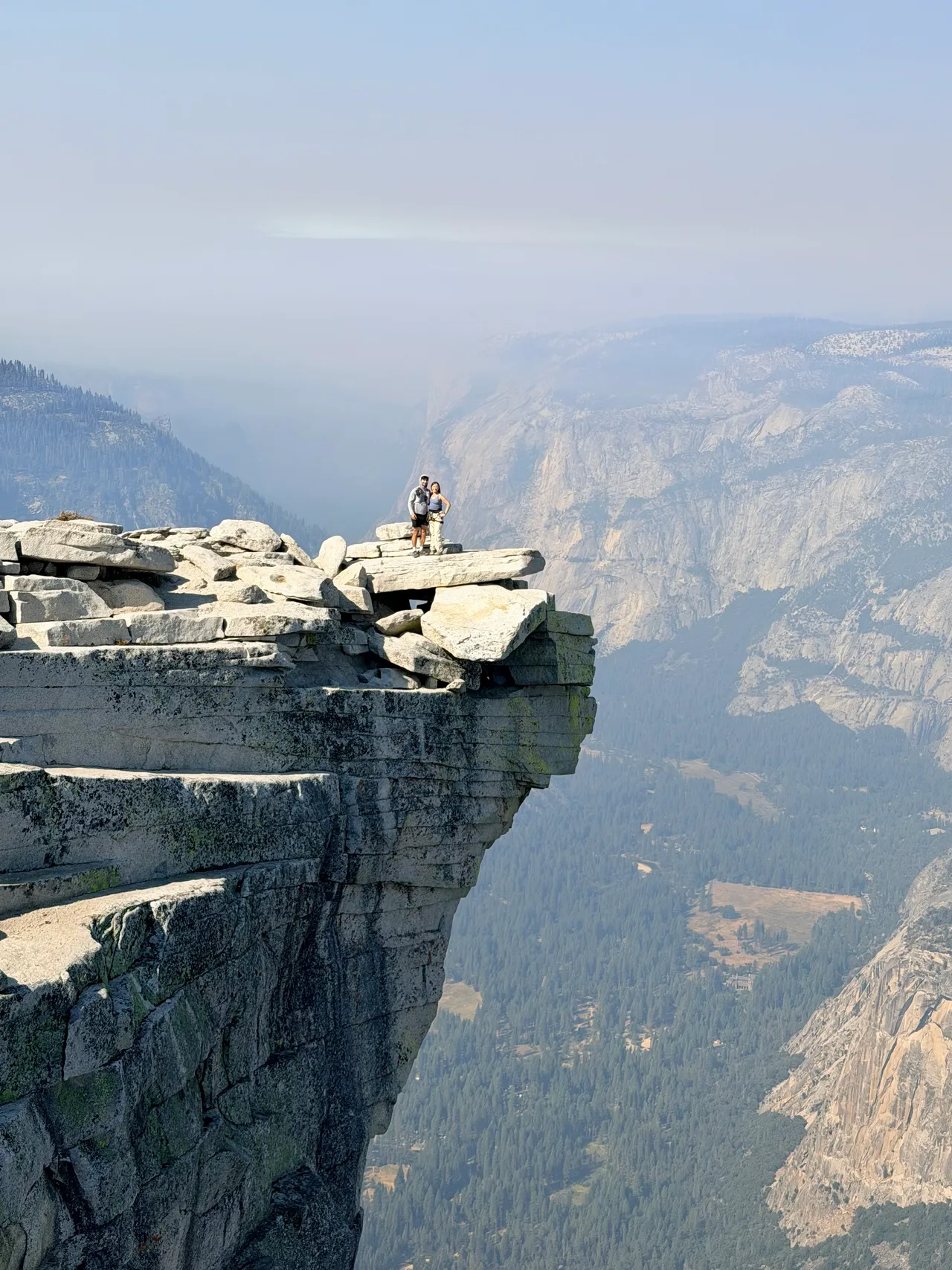 Hikers on the Visor above Yosemite Valley, seen from the summit of Half Dome through wildfire haze