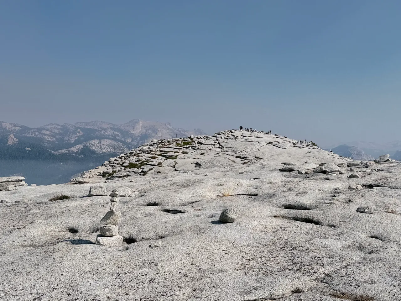 The broad granite summit of Half Dome with hikers scattered across it